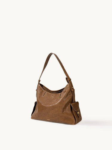 Small Yore Hobo Bag in Sandal color, made from vegetable-tanned leather with exterior flap pockets and adjustable strap.