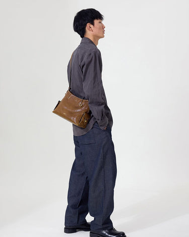 Small Yore Hobo Bag in Sandal color, crafted from vegetable-tanned leather with adjustable strap, worn by a man.