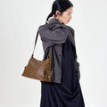 Small Yore Hobo Bag in Sandal leather with adjustable strap and side pocket, modeled by a woman.