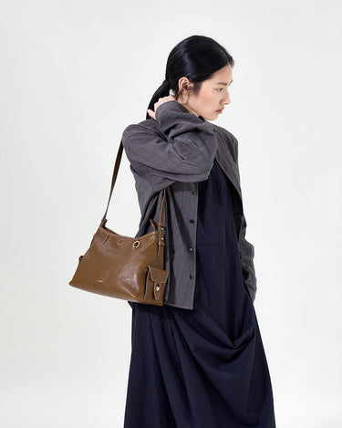 Small Yore Hobo Bag in Sandal leather with adjustable strap and side pocket, modeled by a woman.