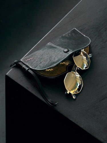 Yore Glasses Case: Black leather, white stitching, gold-rimmed sunglasses, reflective gold lenses, snap closure.