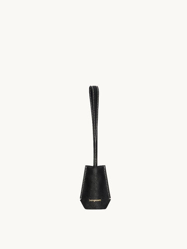 Black Yore keychain tag made of vegetable-tanned leather with gold "songmont" logo and white stitching.