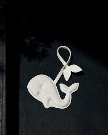 White vegan leather whale charm with tail, made from recycled ocean plastic. Eco-friendly accessory.
