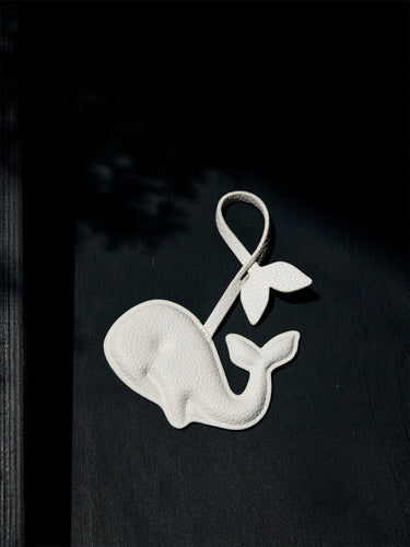 White vegan leather whale charm with tail, made from recycled ocean plastic. Eco-friendly accessory.