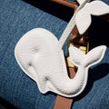 Vegan Charm whale accessory made of white vegan leather on a brown strap, on denim.