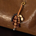 Caramel leather Wish Seeds Charm with mixed beads attached to a brown leather bag.