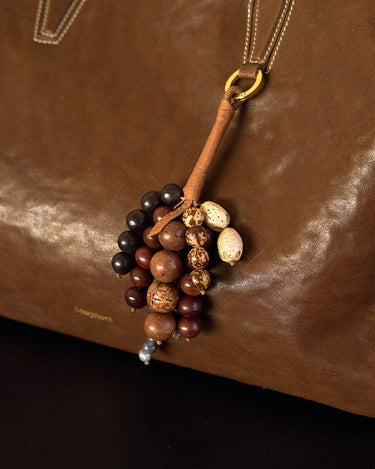 Caramel leather Wish Seeds Charm with mixed beads attached to a brown leather bag.