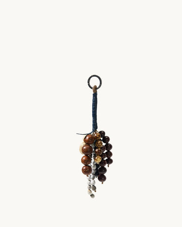 Wish Seeds Charm accessory made with natural Bodhi seeds in brown and white, attached to a blue cord with a metal ring.