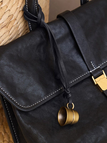 Worry-Free Cup Charm: Black leather bag with brass thimble charm, adjustable strap. Vegetable-tanned leather.